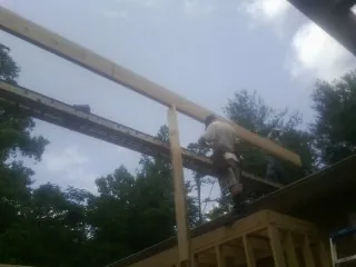 Carpenter setting a ridge beam over a new addition frame — Ice Dam Removal by Roofing Brothers in Rowe