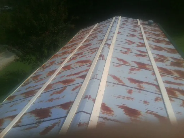 Rusted metal roof panels with new wood purlins before replacement — Storm Damage Roof Repair in Rowe by Roofing Brothers