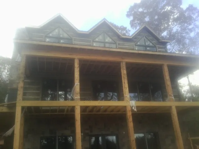 Dormers and porch framing on a large log home under construction — Roof Coating work by our crew in Rowe