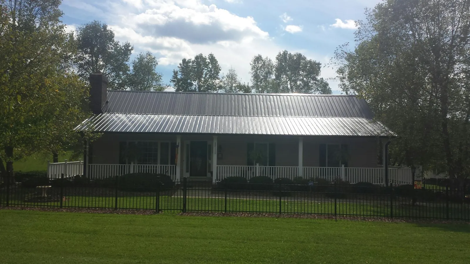 Gray metal roof on a brick ranch with a full width front porch — Gutter Guard Installation work by our crew in Rowe