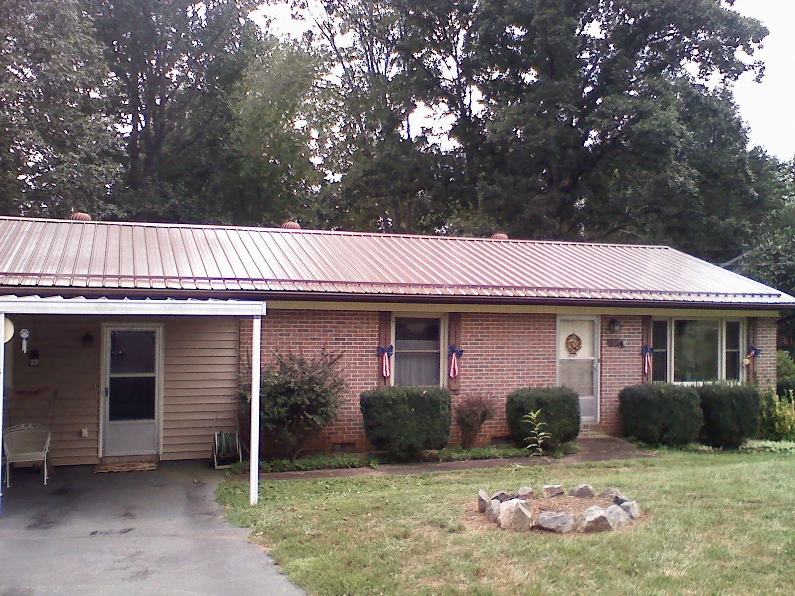 Bronze metal roof and carport on a brick ranch home — Roof Repair work by our crew in Rowe